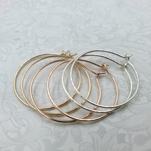 May include: Three pairs of hoop earrings in different sizes. The earrings are made of silver, gold, and rose gold.