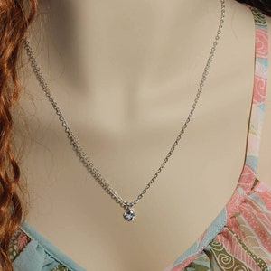 May include: A silver chain necklace with a small, clear crystal pendant.