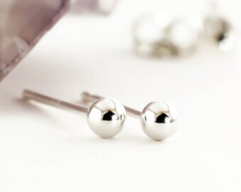 May include: A pair of silver stud earrings with small, round, shiny balls.