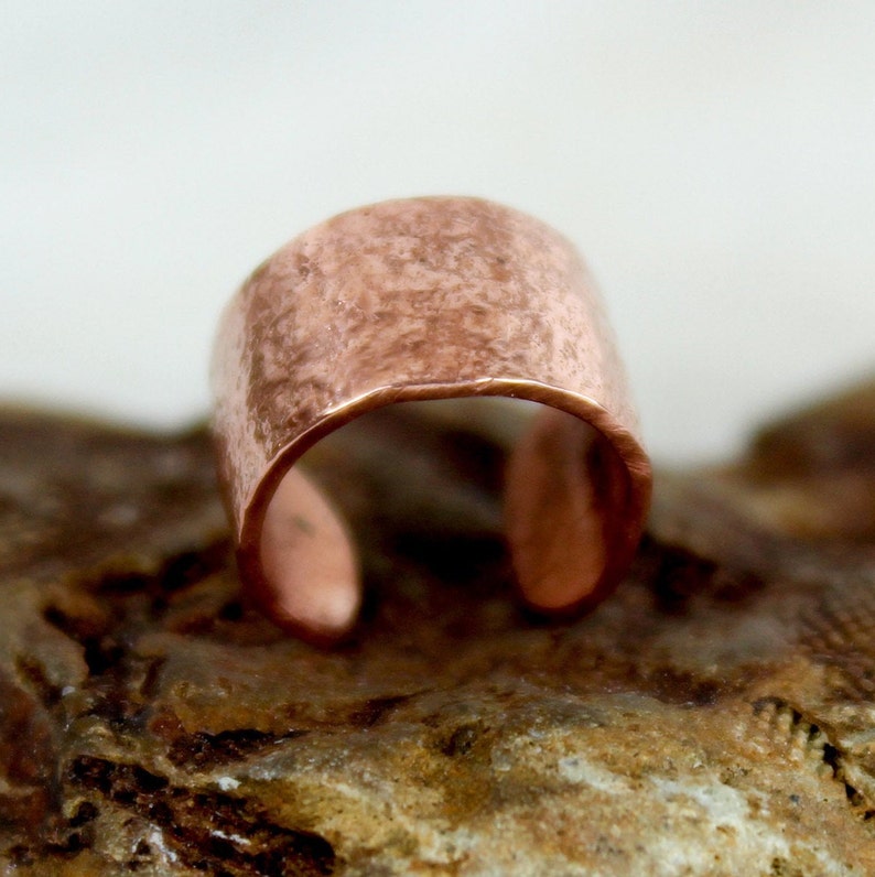 May include: A hammered copper ring with a rustic finish. The ring is open and has a wide band.