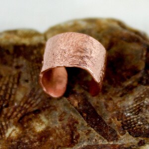 May include: A hammered copper cuff bracelet with a rustic finish.