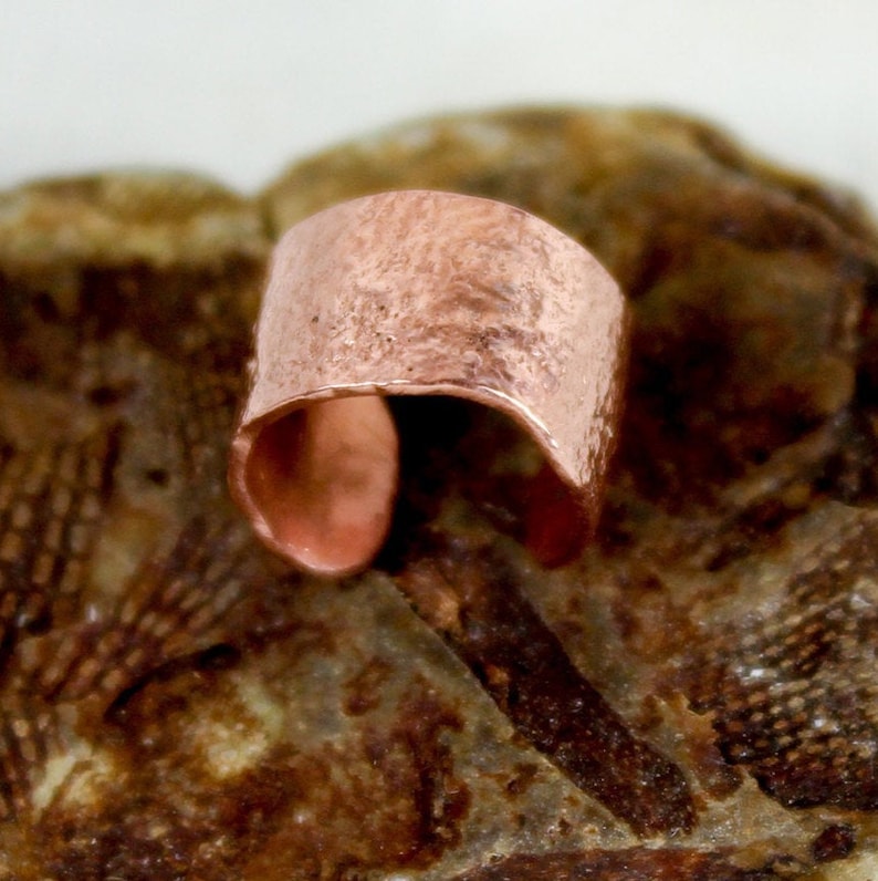 May include: A hammered copper cuff bracelet with a rustic finish.