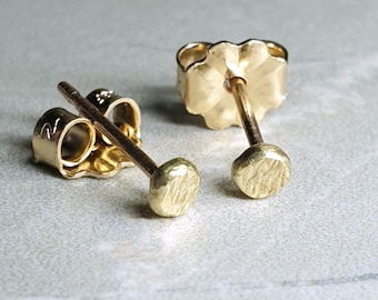 May include: A pair of gold stud earrings with a textured, hammered finish. The earrings are simple and elegant, and would make a great gift.