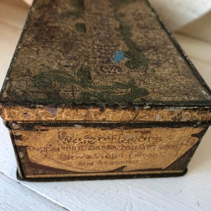 May include: Vintage tin box with a faded, gold-colored label that reads "Wafer Flavors Peppermint, Sassafras, Cinnamon, Clove, Violet, Lemon and Assorted". The box has a green and gold design.