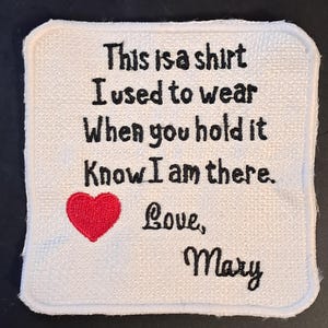 May include: A square white fabric patch with rounded corners featuring black embroidered text that reads: This is a shirt I used to wear When you hold it Know I am there. Love, Mary. A small red embroidered heart is positioned below the text.