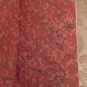 May include: Close-up of the marbled endpapers of a book. The endpapers are a deep red color with a swirling pattern of black and white.