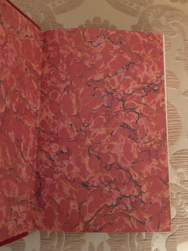 May include: Close-up of the marbled endpapers of a book. The endpapers are a deep red color with a swirling pattern of black and white.