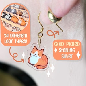 Può includere: Un orecchino in argento sterling placcato oro con un ciondolo trasparente a forma di gatto. Il ciondolo presenta un gatto arancione e bianco in posizione di pagnotta. Il testo sull'immagine recita "34 Different Loaf Types!"