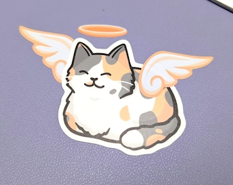 May include: A calico cat with a halo and wings. The cat is smiling and has a white, orange, and black coat.