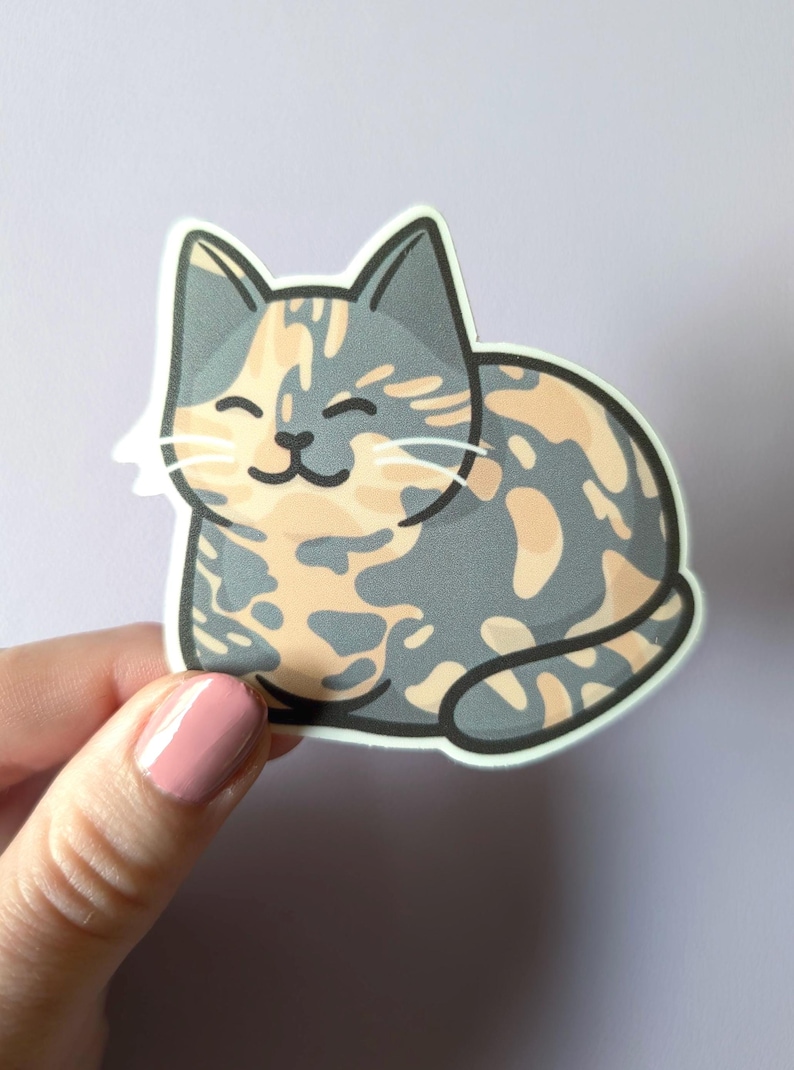 May include: A sticker of a cartoon cat with a calico pattern. The cat is gray, orange, and white with a happy expression. The cat is sitting on its haunches with its tail curled around its body.