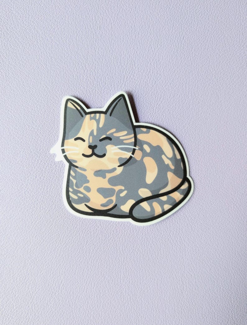 May include: A cartoon sticker of a calico cat with gray, orange, and white fur. The cat is curled up in a sleeping position with its eyes closed and a smile on its face.