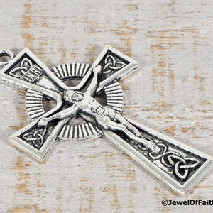 Puede incluir: Un colgante de crucifijo plateado con una representaci&oacute;n detallada de Jesucristo. La cruz presenta dise&ntilde;os de nudos celtas y la inscripci&oacute;n "INRI". El colgante tiene un lazo para colgar y probablemente est&aacute; hecho de metal.