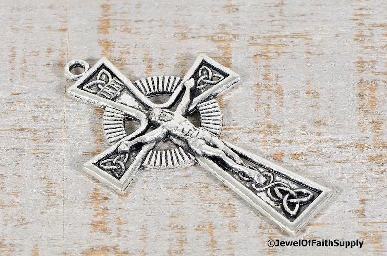 Puede incluir: Un colgante de crucifijo plateado con una representaci&oacute;n detallada de Jesucristo. La cruz presenta dise&ntilde;os de nudos celtas y la inscripci&oacute;n "INRI". El colgante tiene un lazo para colgar y probablemente est&aacute; hecho de metal.