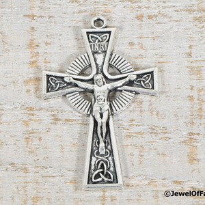 Puede incluir: Colgante de cruz celta plateado con la figura de Jesucristo. La cruz presenta intrincados dise&ntilde;os de nudos y las letras INRI. El colgante est&aacute; dise&ntilde;ado con un lazo para colgar, ideal para un collar.