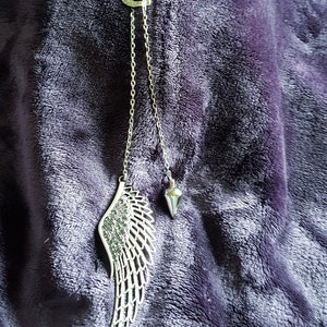 May include: A silver necklace with a heart charm, a wing pendant, and a small cone-shaped pendant.