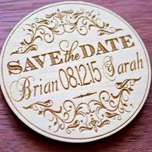 May include: Round wooden save the date magnet with a decorative floral design. The text reads "Save the Date Brian 08.12.15 & Sarah".