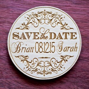 May include: A round wooden save the date sign with a decorative border and the text "Save the Date Brian 08.12.15 Sarah".
