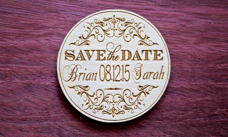 May include: A round wooden save the date sign with a decorative border and the text "Save the Date Brian 08.12.15 Sarah".