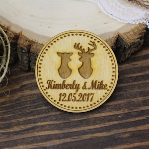 May include: A round wooden disc with a couple of deer silhouettes and the text "Kimberly & Mike 12.05.2017" engraved on it.