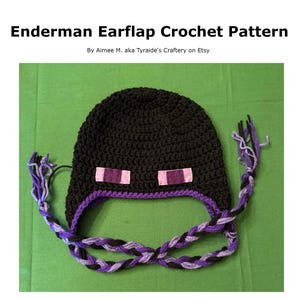 Puede incluir: Gorro de orejeras Enderman negro de ganchillo con lazos trenzados morados y negros. El gorro presenta dos rectángulos rosas para los ojos y el texto "Enderman Earflap Crochet Pattern".