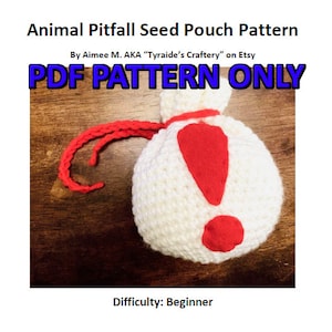 May include: A white crocheted pouch with a red exclamation point on the front. The pouch has a red drawstring and is labeled "PDF PATTERN ONLY".