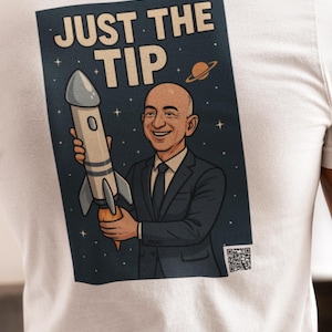 May include: White t-shirt with a graphic on the back. The graphic shows a cartoon of a man in a suit holding a rocket, with the text "JUST THE TIP" and a QR code.