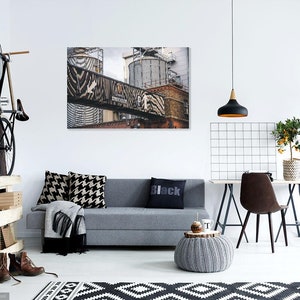 May include: A modern living room interior with a gray sofa, black and white patterned pillows, a black throw blanket, a black and white rug, a gray knitted ottoman, a black pendant light, a black and white grid wall decor, a wooden table with a brown chair, a potted citrus tree, a black studio light, and a bicycle hanging on a wooden wall.