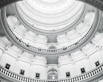 May include: A black and white photograph of a white, circular, domed ceiling with intricate details and multiple levels of balconies.