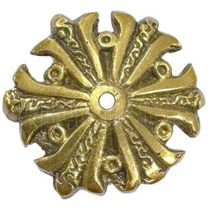 May include: A gold-colored metal decorative piece with a circular shape and a central hole. The piece has a starburst design with intricate details and a textured surface.