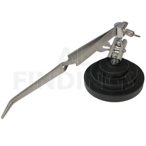 May include: A silver-toned, adjustable, third hand soldering tool with a black base. The tool has a long, curved arm with a pair of tweezers at the end.