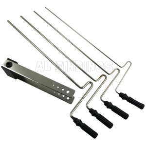 May include: A set of five silver-toned metal coat hangers with black plastic handles. The hangers have a hook on one end and a curved shape on the other end. The hangers are designed to be used for hanging clothes.