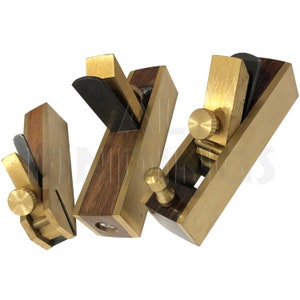 May include: Three small wood and brass hand planes with black blades. The planes are arranged in a triangular shape.
