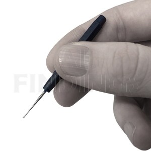 May include: A close-up of a small, blue, metal tool with a pointed tip. The tool is held in a gloved hand.