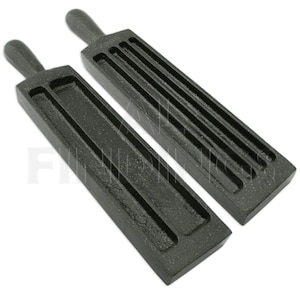 May include: Two black metal ingot molds with handles. Each mold has a rectangular shape with multiple grooves for shaping metal. The molds are made of a textured, dark material and are designed for crafting.