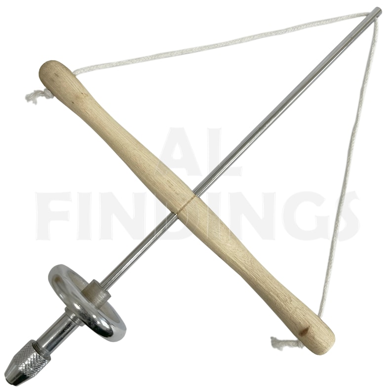 May include: A silver metal hand drill with a wooden handle and a white string attached to the top. The drill has a chuck at the bottom and a ring around the center.