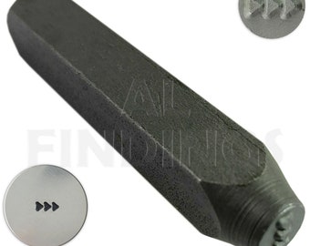 Pode incluir: Um carimbo de metal preto com uma pega hexagonal e uma cabeça redonda. A cabeça é gravada com três setas apontando para a direita. O carimbo é usado para marcar metal.