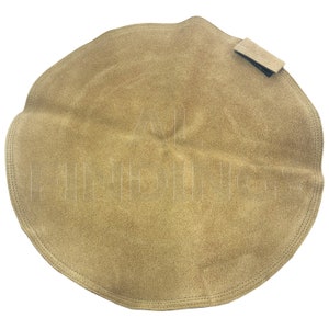 Peut inclure: Un tampon de polissage rond en cuir de couleur beige avec une petite sangle en cuir noir attachée au sommet.