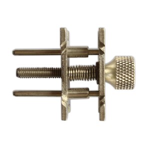 May include: A metal clamp with a spring and a threaded knob. The clamp has two sets of prongs that can be adjusted to hold an object.