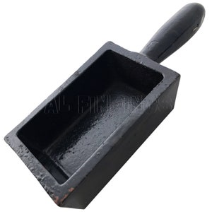 May include: Black cast iron ingot mold with a handle. The mold is rectangular with a smooth, shiny interior.