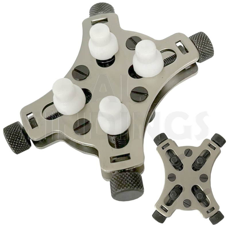 May include: A silver watch case holder with four adjustable arms and white plastic inserts. The holder is designed to securely hold a watch case while working on it. The holder is shown in two positions, one with the arms extended and the other with the arms retracted.