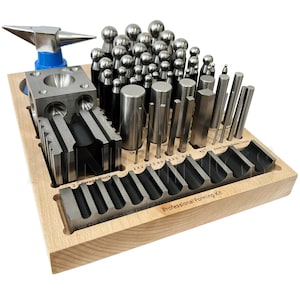 May include: A wooden box filled with metal jewellery making tools. The tools include a variety of sizes and shapes of metal punches, a small anvil, and a metal block with different shaped holes. The box is labelled "Professional Forming Kit".