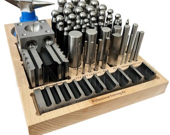 May include: A wooden box filled with metal jewelry making tools. The tools include a variety of sizes and shapes of metal punches, a small anvil, and a metal block with different shaped holes. The box is labeled "Professional Forming Kit".
