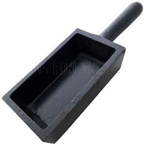 May include: Black cast iron ingot mold with a handle. The mold is rectangular with a smooth, flat interior.