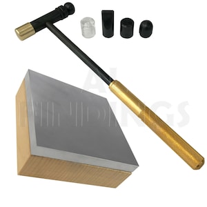 May include: A gold and black metal hammer with a wooden base and four interchangeable tips. The tips include a clear plastic tip, a black rubber tip, and two black metal tips.