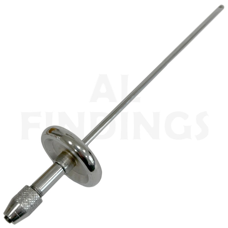 May include: A silver metal drill chuck with a long, thin shaft. The chuck has a knurled handle and a round, flat base.