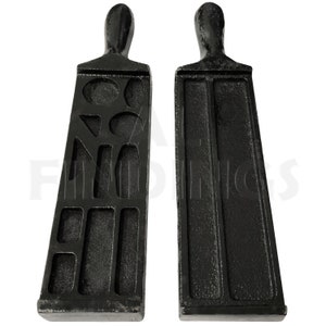 May include: Two black metal jewellery making moulds. One mould features various geometric shapes, while the other has two long rectangular channels. Both moulds have a handle at the top.