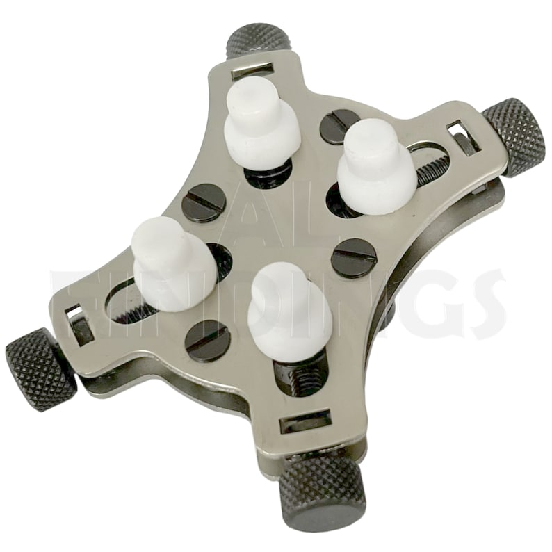 May include: A silver watch case holder with four white adjustable knobs and three black knobs. The holder is designed to hold a watch securely while working on it.