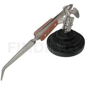 May include: A silver-toned, adjustable, third-hand soldering tool with a wooden handle and a black, circular base. The tool is designed to hold small objects in place while soldering.