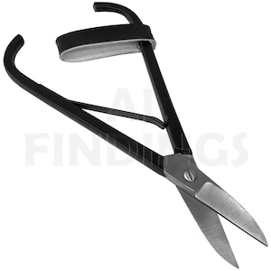 Puede incluir: Tijeras de metal negro con mangos curvos y una sección de hoja de metal plateado. La herramienta cuenta con un mecanismo de resorte y una correa similar al cuero unida al área del mango superior. La palabra FINDINGS es visible en el fondo.