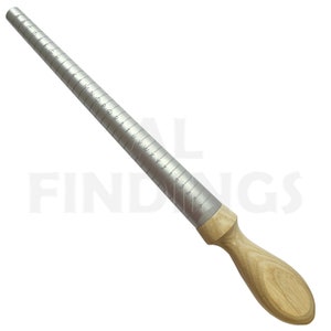 Puede incluir: Un medidor de anillos de metal plateado con mango de madera. El medidor tiene marcas para tallas de anillos espa&ntilde;olas y tama&ntilde;o alfab&eacute;tico.